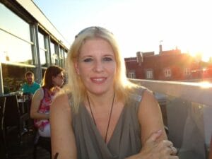 A blonde woman sitting at a table in a restaurant.