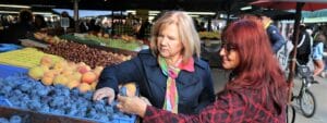 Two women buying fruit at an outdoor market.