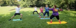 A group of people doing yoga in a park.
