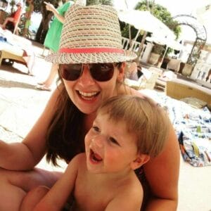 A woman in a hat with a child on the beach.