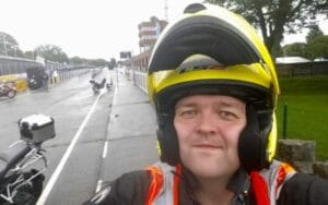 A man in a helmet taking a selfie on a motorcycle.