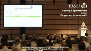 A woman is giving a speech in front of an audience.
