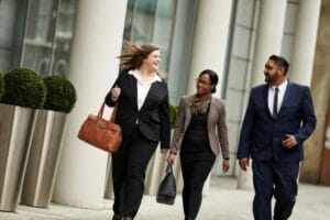 Three business people walking down a city street.