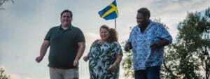 Three people standing in front of a swedish flag.