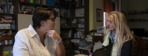 Two women sitting at a table talking to each other.