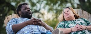 A man and woman sitting in a wooden chair.