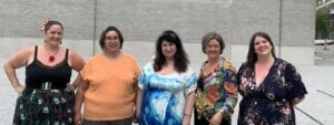 A group of women posing for a photo in front of a building.