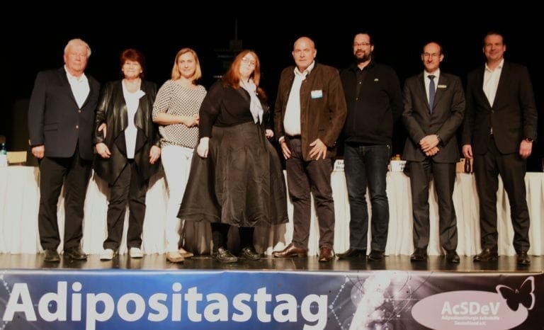A group of people standing in front of a sign that says adipoststag.