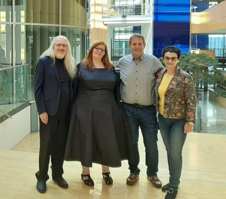Four people posing for a photo in an office building.