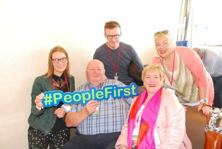 A group of people posing with a sign that says people first.