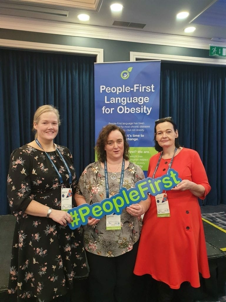 Three women holding a sign that says people first language society.