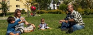 A family sits on the grass and plays with a frisbee.