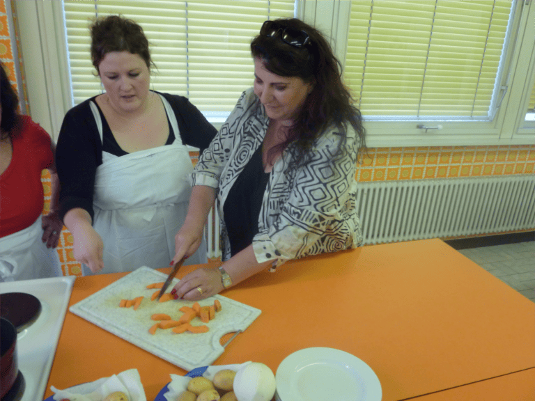 A woman cutting carrots on a cutting board.
