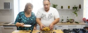 A man and woman preparing food in a kitchen.