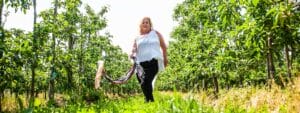 A woman walking through an orchard.