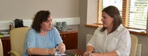 Two women sitting at a table talking to each other.