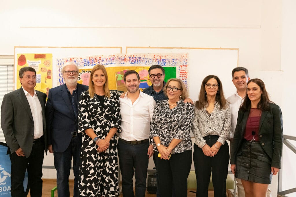 A group of people posing for a photo in front of a painting.