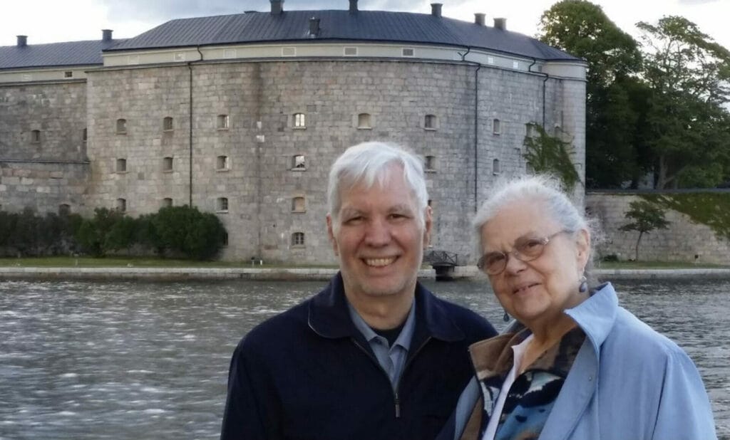 A man and woman standing in front of a castle.