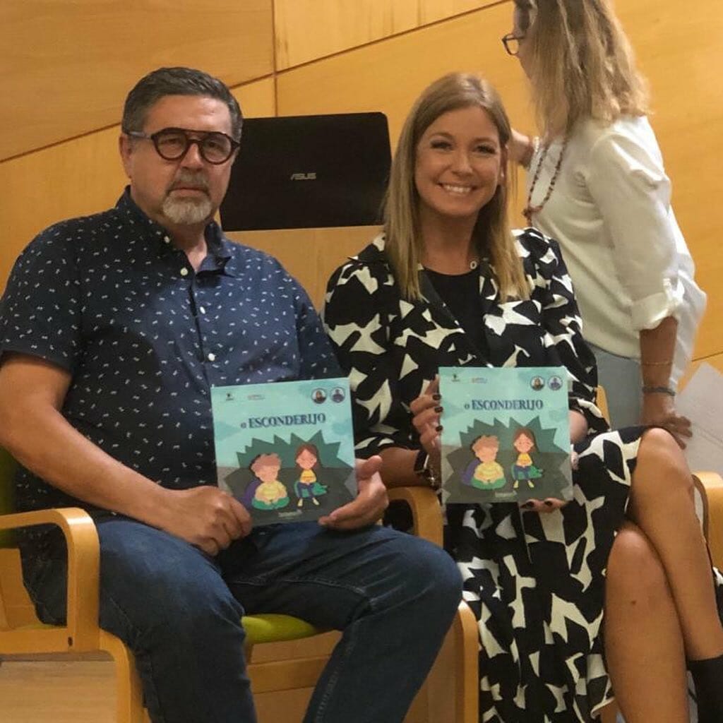 Two people sitting on chairs holding books.
