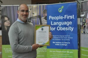 A man holding up a certificate for people first language for obesity.