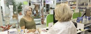 A woman is standing in front of a mirror in a pharmacy.