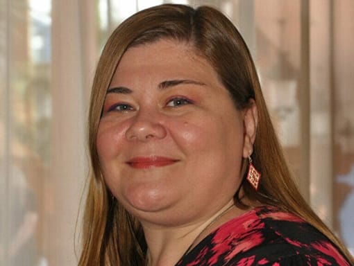 A woman in a floral top smiles for the camera.