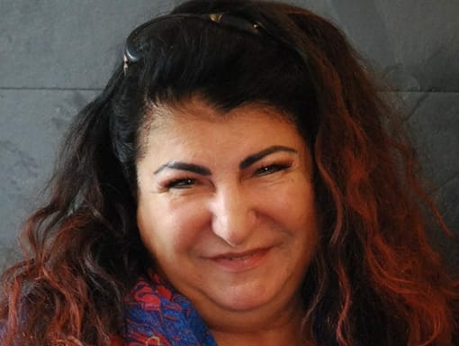 A woman with long curly hair smiling for the camera.