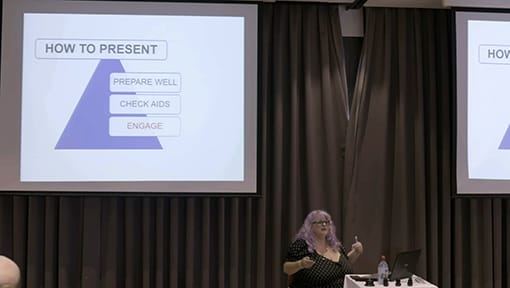 A woman giving a presentation in front of a screen.