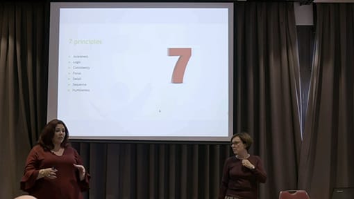Two women standing in front of a projection screen.