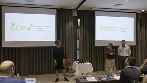 A group of people standing in front of a screen.