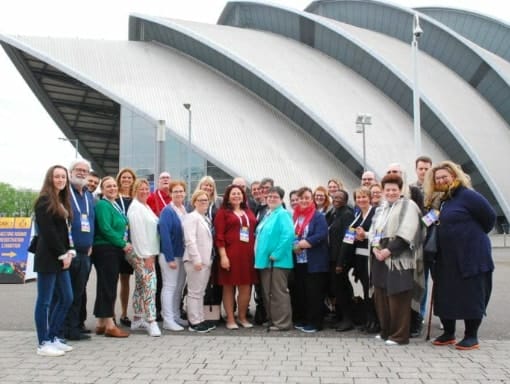 A group of people posing in front of a large building.