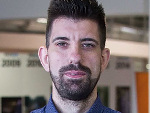 A man in a blue shirt with a beard.