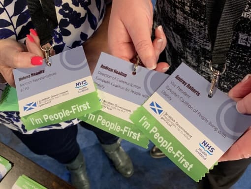 Two people holding up badges at a conference.