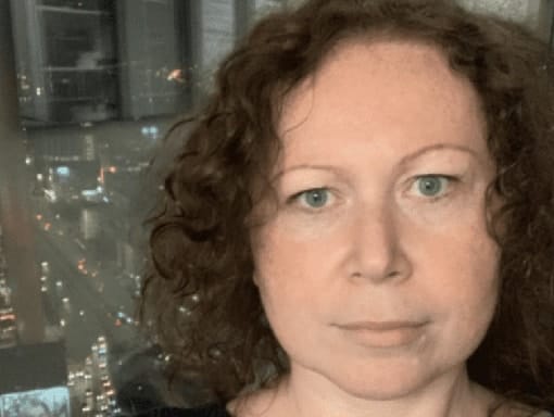 A woman with curly hair in front of a city skyline.