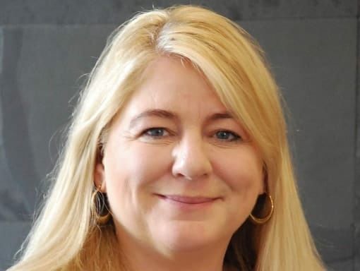 A woman with long blonde hair smiling for the camera.