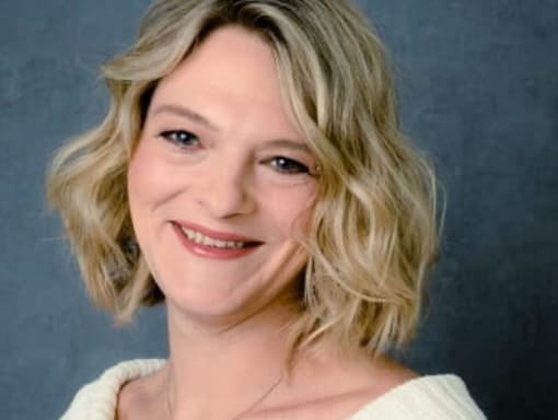 A woman in a white sweater smiling for the camera.