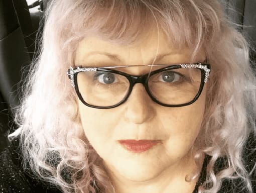 A woman with glasses and a black shirt.