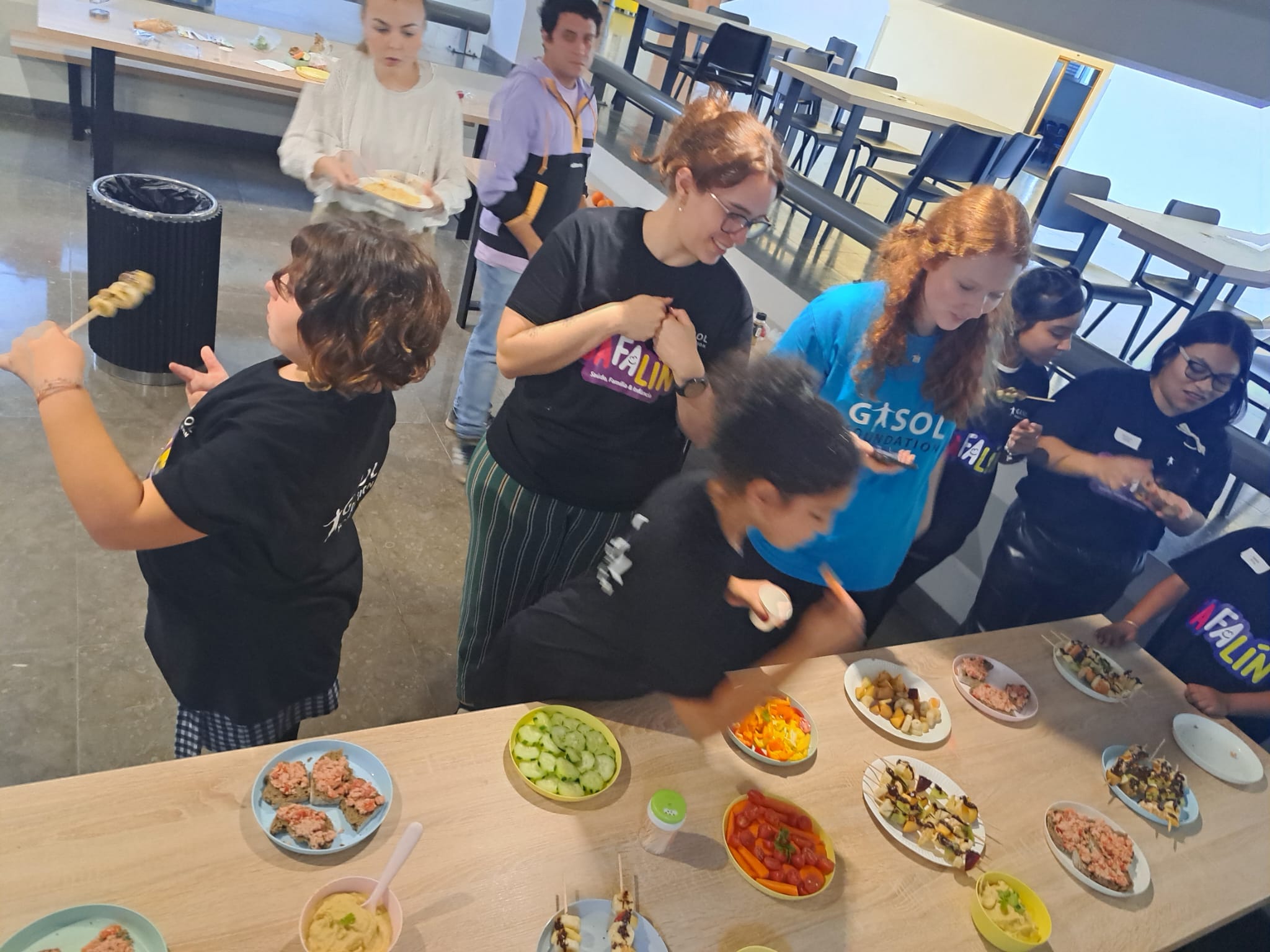 People serving food from a table with various dishes in a communal setting.