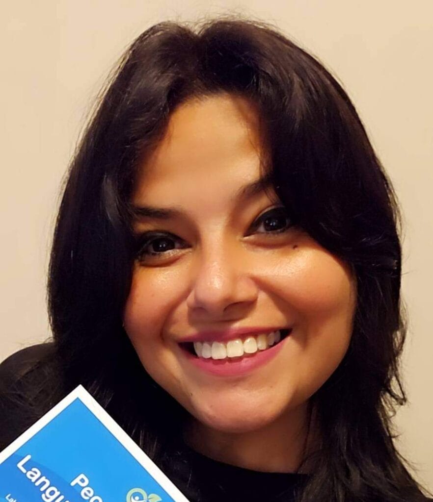 Person smiling, holding a flyer titled "People-First Language for Obesity," wearing a button with "ECP4" on it.